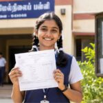 A student checking Tamil Nadu Class 10 Result 2026 with a printed marksheet outside a school